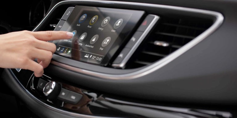 A driver interacting with the 2023 Buick Enclave infotainment console