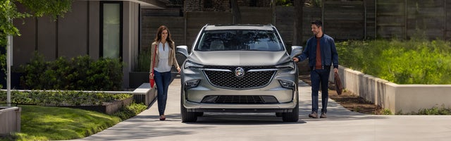 A man and woman prepare to enter a Buick Enclave parked in a driveway