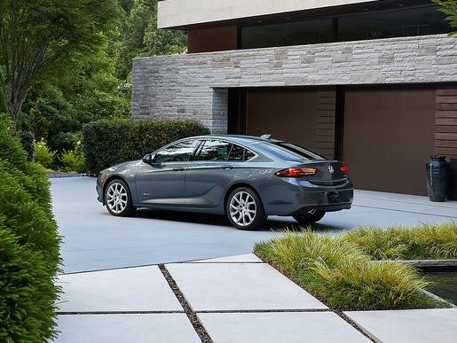 Driver Side View of the 2019 Buick Regal Sportback Avenir Luxury Coupe Parked by a garage