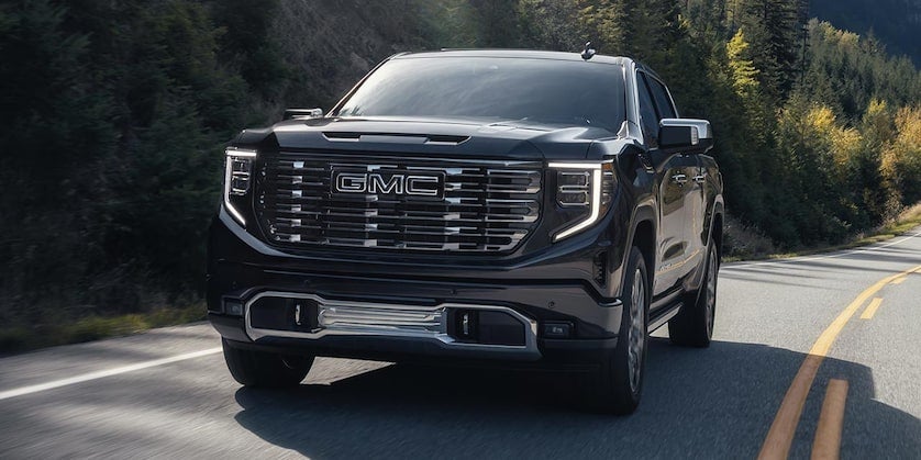 2025 GMC Sierra 1500 Denali Ultimate driving on a forested highway