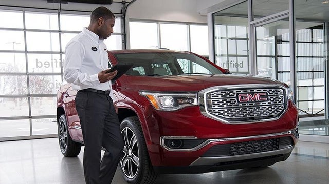 A Certified technician inspects a GMC vehicle in a service bay at a dealership
