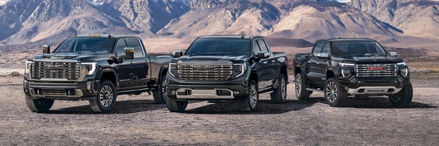 Lineup of GMC Trucks Parked Side by Side With Mountains in the Background