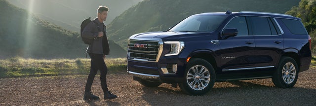 Man walking to a GMC Yukon SUV in a mountainous scene