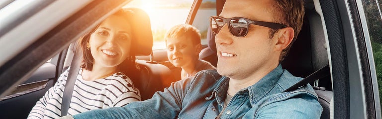 A family riding in a car with the sunshining through the vechicle cabin